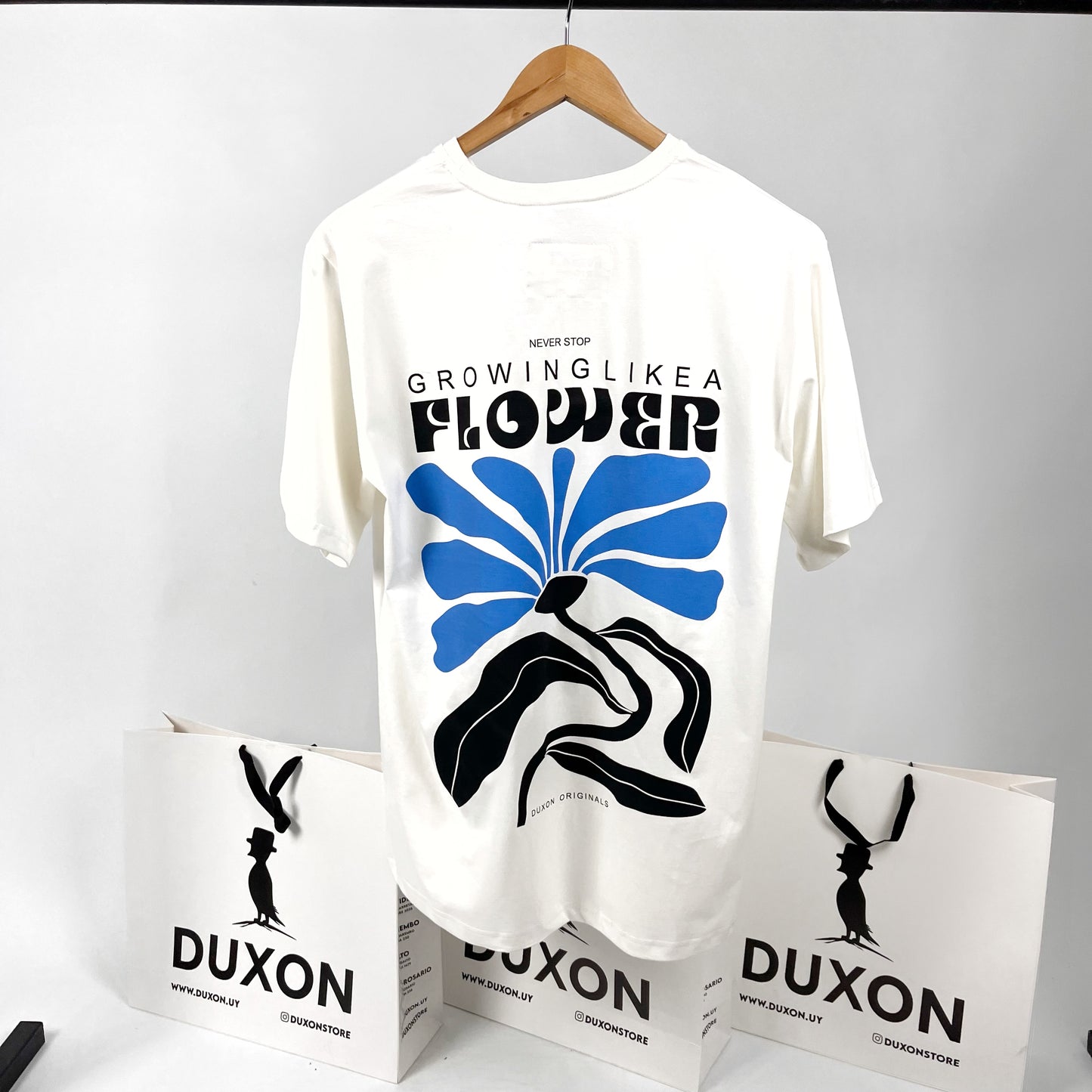 Remera blanca “Neber Stop” flower con estampa en negro y azul