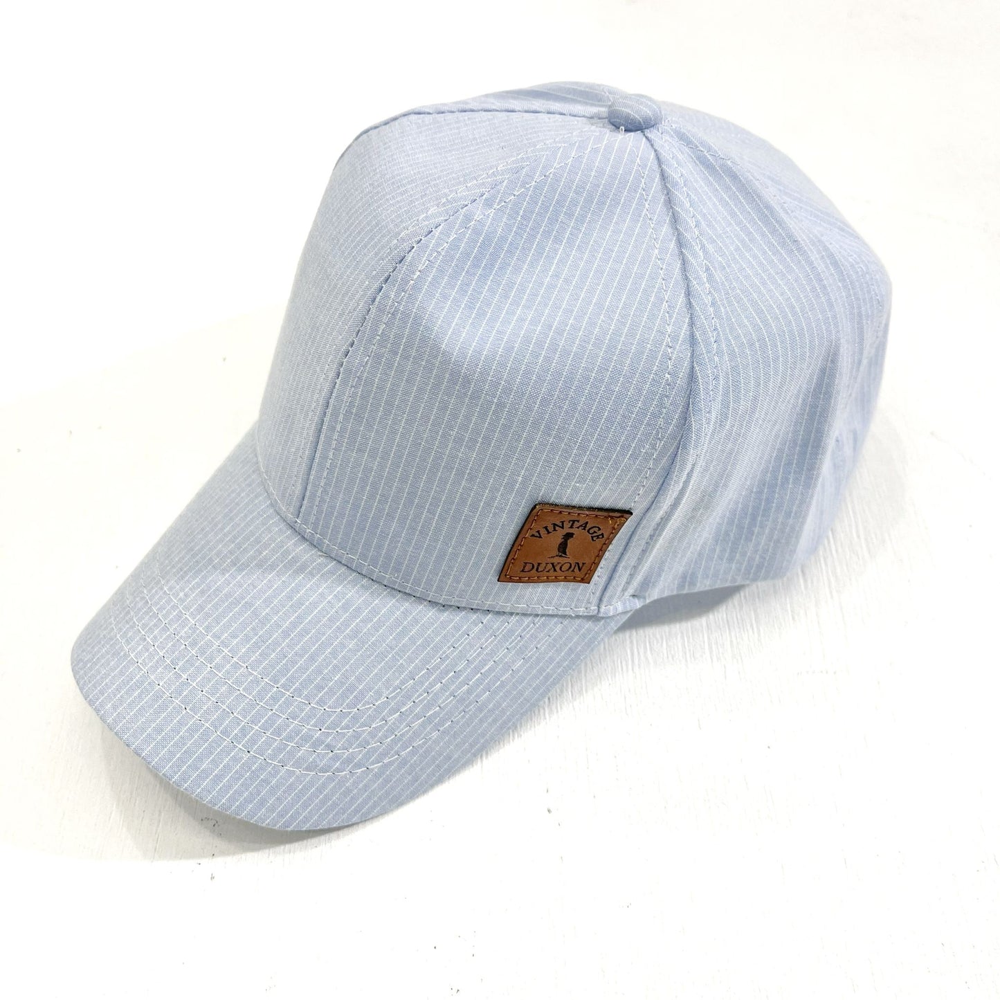 GORRA DE TELA CON VISERA A RAYAS CELESTE