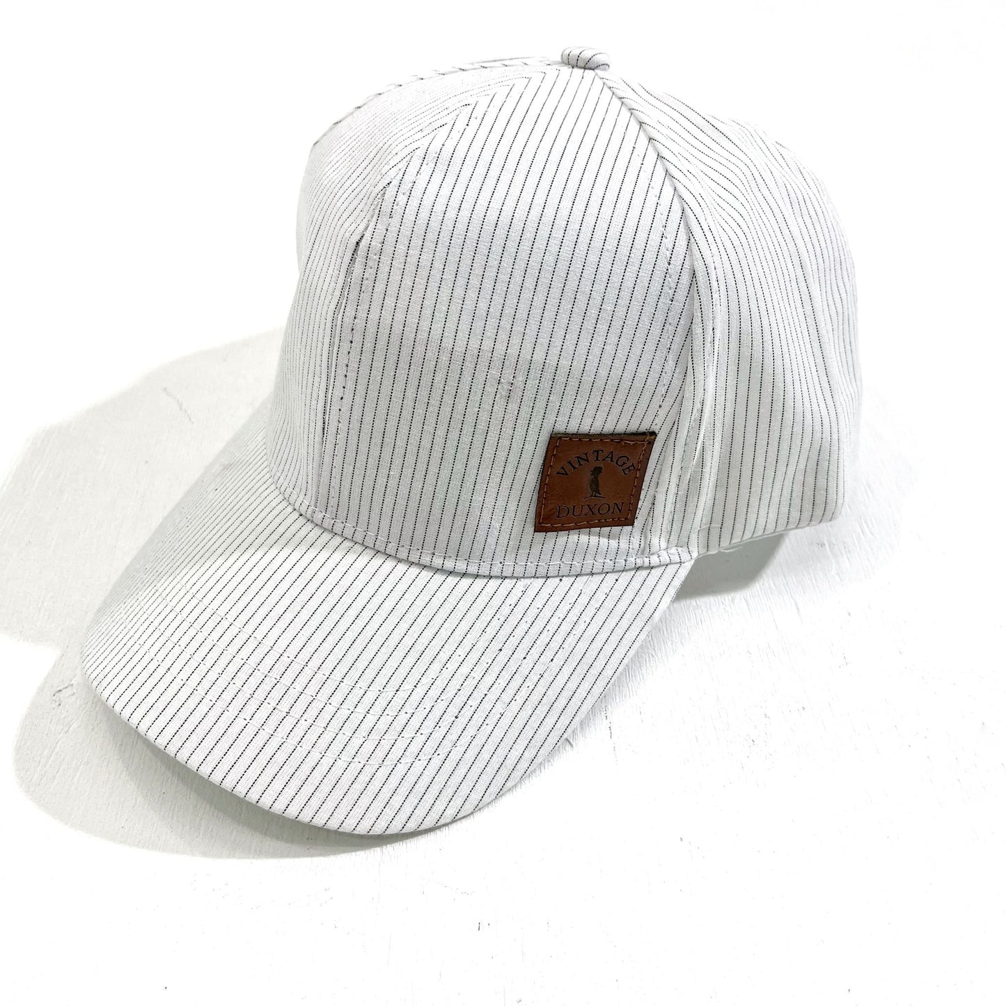 GORRA DE TELA CON VISERA A RAYAS BLANO
