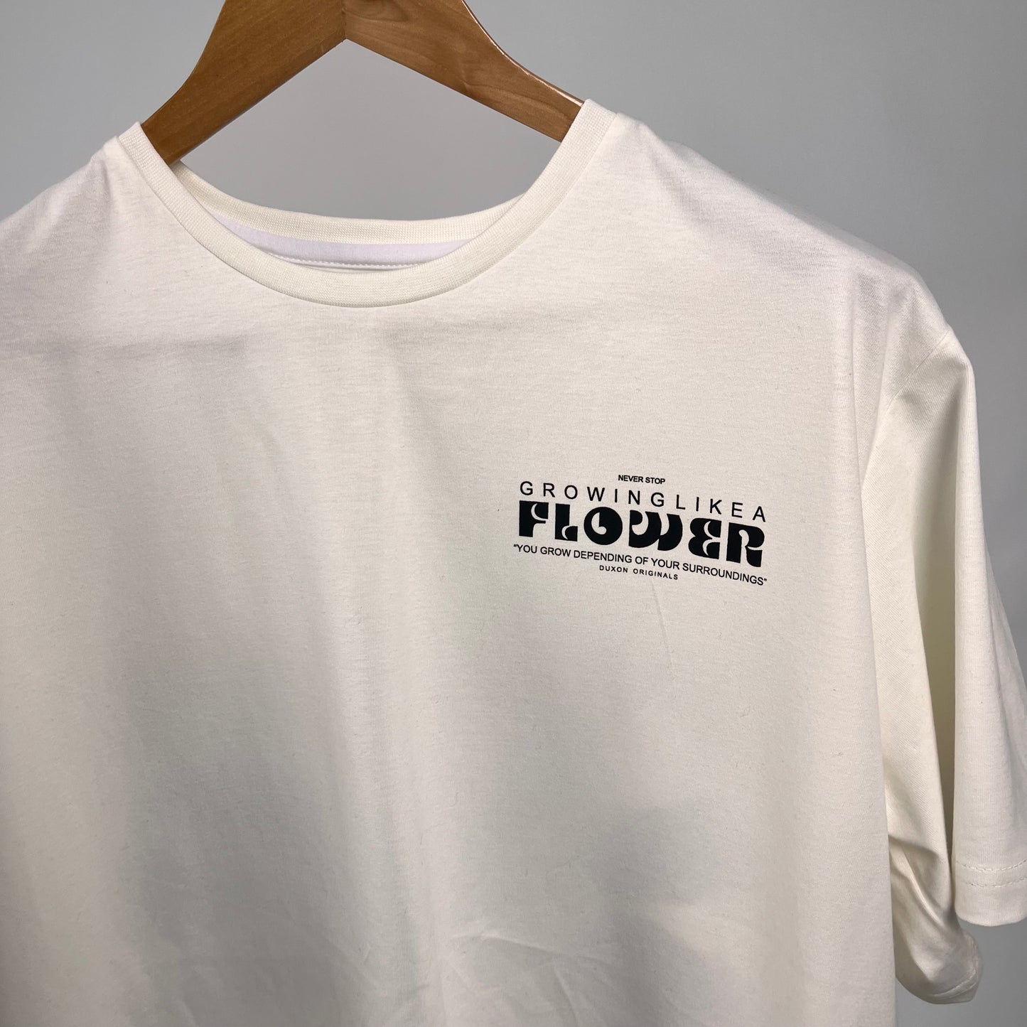 Remera blanca “Neber Stop” flower con estampa en negro y azul